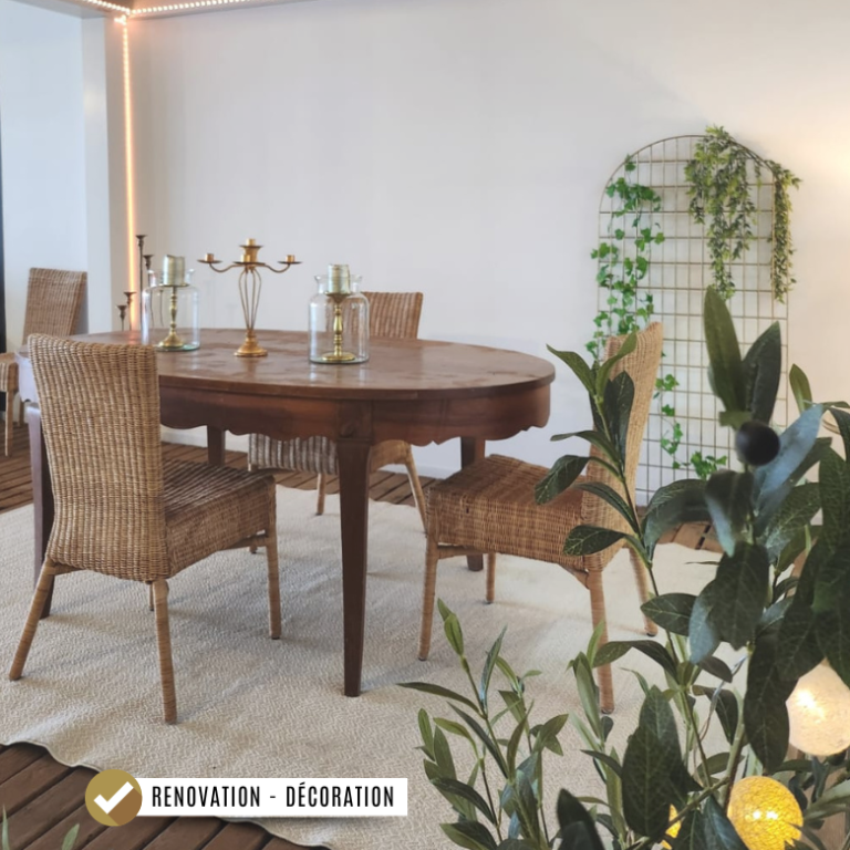 Table en bois avec des chaises en osier, décorée de plantes vertes, sous une pergola bioclimatique
