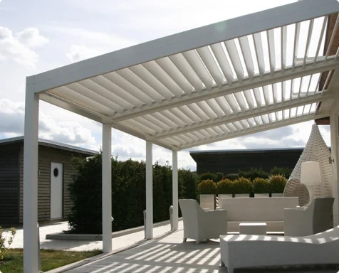 Terrasse moderne avec pergola blanche et mobilier extérieur, sous un ciel nuageux.
