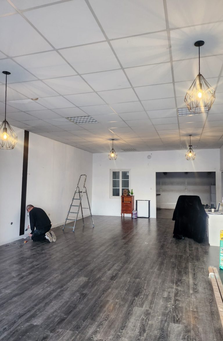 Intérieur d'un espace vide avec un homme s'occupant de la décoration, éclairage suspendu.