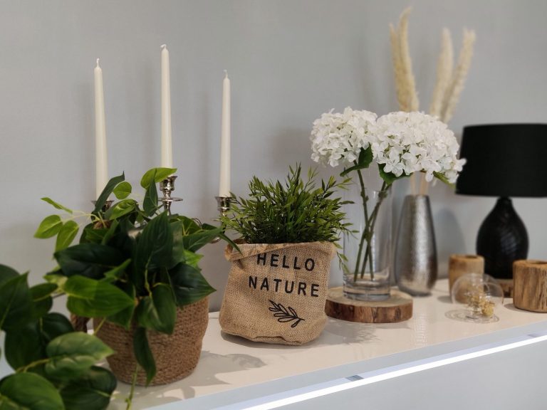 Vases et bougies décoratives avec des plantes et des fleurs sur une étagère.