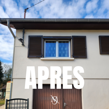 Façade d'une maison avec fenêtres à volets, portail en bois et ciel nuageux.